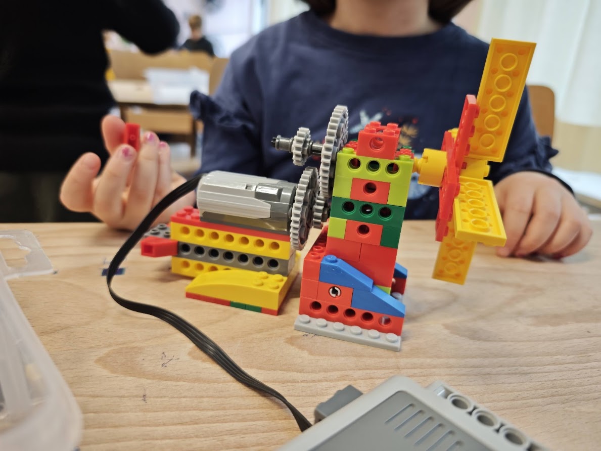Kind baut ein motorisiertes LEGO-Modell im Feriencamp